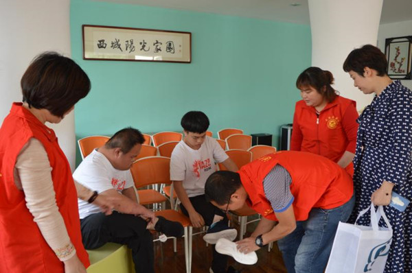 志愿者帮助残疾人试穿新鞋.jpg